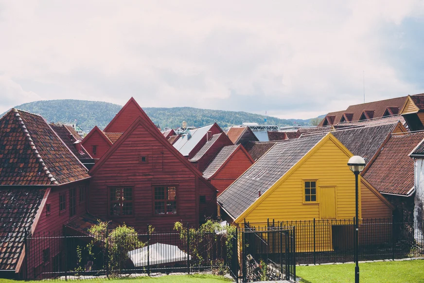Red and yellow wooden houses with tiled roofs and hills in the distance